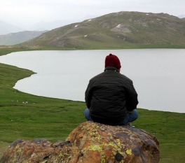 traveling solo- Person sitting on a rock overlooking a lake